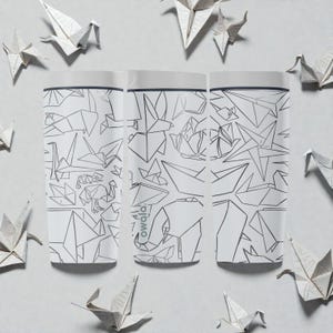 K&ouml;nnte beinhalten: Drei wei&szlig;e Owala-Wasserflaschen mit einem geometrischen Origami-Design in Schwarz. Die Flaschen sind von Origami-Papierkranichen umgeben. Die Flaschen haben einen wei&szlig;en Deckel und das Owala-Logo ist auf der Seite sichtbar.