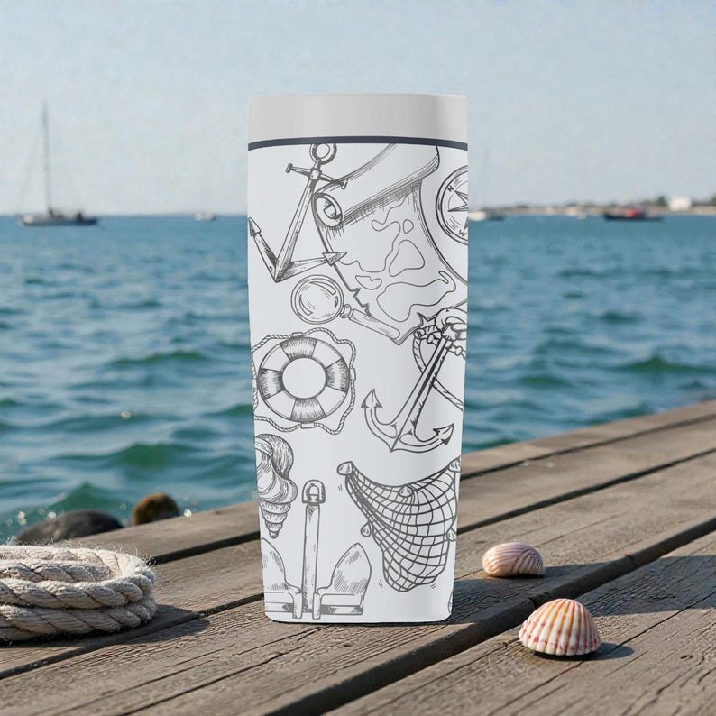 May include: A white tumbler featuring a nautical-themed design with black line art. The artwork includes anchors, a compass, a map, a life preserver, and a fishing net. The tumbler has a white lid and is set against a backdrop of a wooden dock and the ocean.