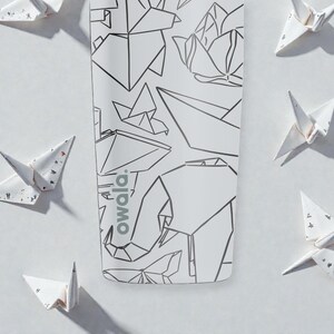 K&ouml;nnte beinhalten: Wei&szlig;e Wasserflasche mit geometrischem Design mit einem Elefanten und anderen Formen. Auf der Flasche steht das Wort "owala". Origami-Papierkraniche sind auf wei&szlig;em Hintergrund um die Flasche herum verstreut.