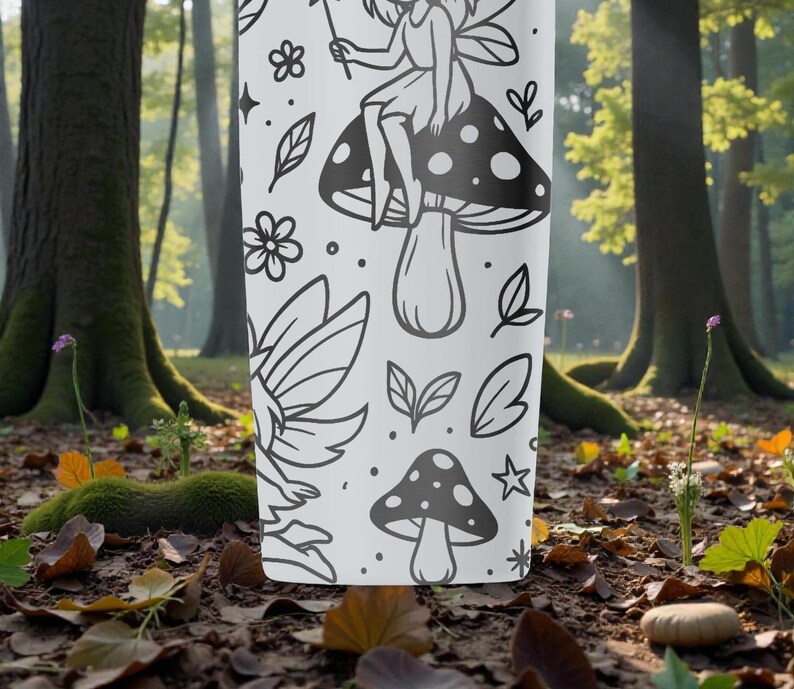 May include: A white tumbler with a black fairy and mushroom design. The design includes a fairy on a mushroom, plus other botanical elements. The tumbler is set against a blurred forest background.