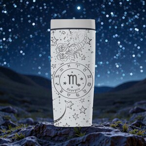 May include: A white travel mug featuring a black Scorpio zodiac design. The design includes a scorpion, roses, stars, and the Scorpio symbol. The mug has a white lid and is set against a starry night background.