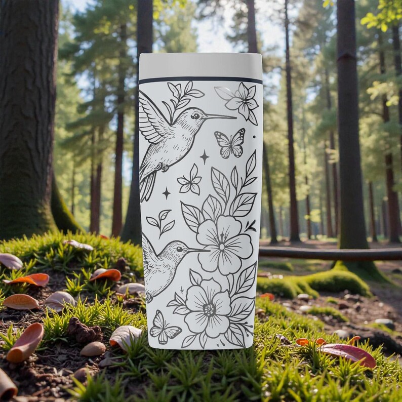 Puede incluir: Un termo blanco con un dise&ntilde;o floral y colibr&iacute;es en blanco y negro. El dise&ntilde;o incluye colibr&iacute;es, flores, mariposas y hojas. El termo es cil&iacute;ndrico y parece estar hecho de acero inoxidable.