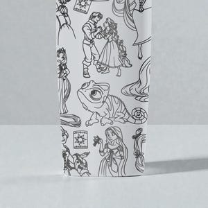 May include: White tumbler featuring black line art illustrations of characters and elements from a fairy tale. The design includes a princess, a prince, a chameleon, and other related imagery.