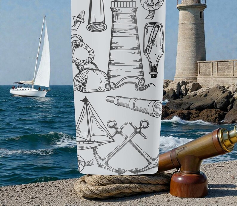 May include: A white tumbler featuring nautical illustrations of anchors, lighthouses, and sailboats. A vintage-style telescope sits on a wooden base. A sailboat is in the background, sailing on the blue ocean. The tumbler is resting on a thick rope.