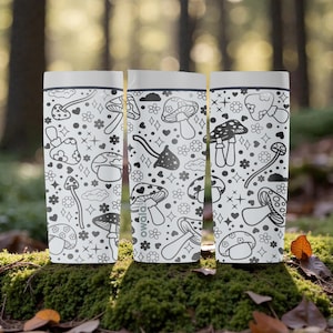 Peut inclure: Trois gourdes blanches avec un motif de champignons noir et blanc r&eacute;p&eacute;t&eacute;. Les bouteilles ont un couvercle blanc et sont pos&eacute;es sur une surface moussue. La marque "owala" est visible sur une bouteille.