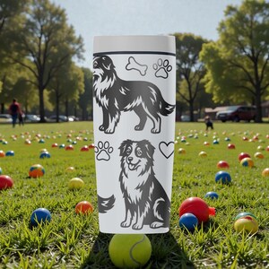 Puede incluir: Vaso blanco con ilustraciones de perros negros, huellas de patas, un hueso y un coraz&oacute;n. El vaso tiene tapa y est&aacute; rodeado de bolas de colores en un campo de hierba. El dise&ntilde;o incluye dos razas de perros diferentes.