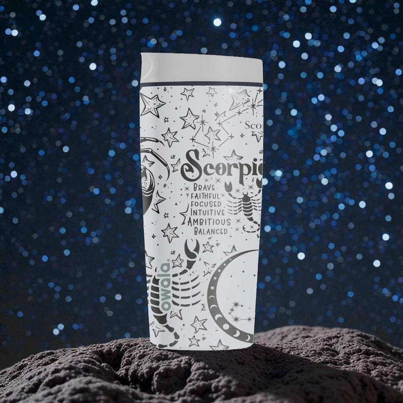 May include: White travel tumbler with a black Scorpio zodiac design. The design includes the word "Scorpio", a scorpion, stars, and the words "brave, faithful, focused, intuitive, ambitious, balanced". The tumbler has a white lid.