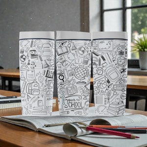 May include: Three white rectangular tumblers with lids, each covered in black and white school-themed doodles. The phrase "Back to School" is visible on one tumbler. The tumblers are on a wooden desk with an open book and pencils.