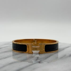 Bracelet Hermès Clic H Noir Et Doré - Élégance Intemporelle, Parfait Pour Un Look Chic