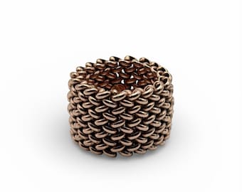 May include: A rose gold ring with a woven chain design. The ring is a continuous band of interlocking links, creating a textured surface. The ring is set against a white background.