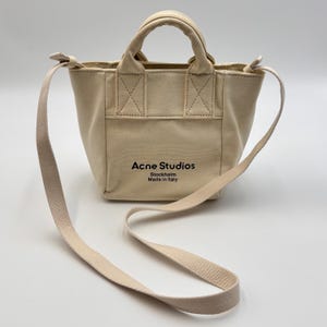 May include: A set of three ceramic mugs with a speckled, matte finish. The mugs are in shades of cream, light gray, and dark gray. Each mug has a simple, minimalist design and a rounded handle.