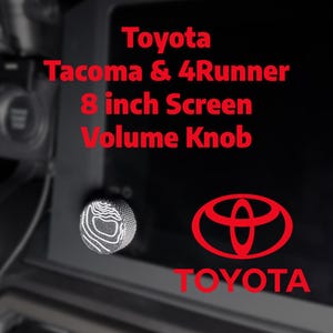May include: A black car dashboard with a silver volume knob. The knob has a white topographic design. Red text reads "Toyota Tacoma & 4Runner 8 inch Screen Volume Knob" and the Toyota logo.