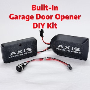 May include: Black garage door opener DIY kit with the text "Built-In Garage Door Opener DIY Kit". The kit includes two black modules with the "AXIS PRECISION WORKS" logo and a black button.