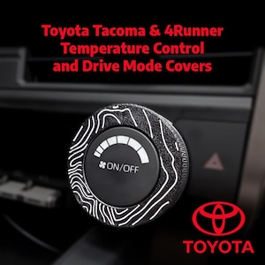 May include: Black temperature control knob cover with white topographic design for Toyota Tacoma & 4Runner vehicles. The knob features an on/off symbol and a temperature gauge. The Toyota logo is visible in the lower right corner.