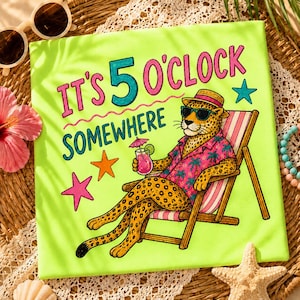 Puede incluir: Una camiseta verde neón con la frase "It's 5 O'Clock Somewhere" y un leopardo de dibujos animados con gafas de sol y una camisa hawaiana, relajándose en una tumbona. La camiseta también presenta estrellas y un cóctel.
