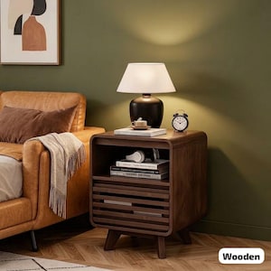 May include: A dark brown wooden nightstand with a lamp, books, and an alarm clock. The nightstand has a drawer with horizontal slats and a shelf. A white lamp with a black base sits on top. The nightstand is next to a brown leather couch.