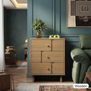 May include: A light oak wooden dresser with four drawers and a unique design. The dresser has a rectangular shape and is set against a teal wall. A vase with greenery and a tray of green apples sit on top. The word "Wooden" is in the image.