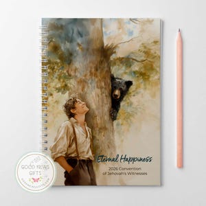 May include: A spiral-bound notebook with a watercolor illustration of a young person looking up at a tree, with a bear peeking out. The notebook has the text "Eternal Happiness" and "2026 Convention of Jehovah's Witnesses". A peach-colored pencil rests on the side.