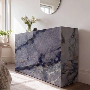 May include: A rectangular console table featuring a polished blue and grey marble finish with prominent white veining. The piece has a solid, block-like structure with clean, sharp edges and a smooth, reflective surface texture throughout its exterior.