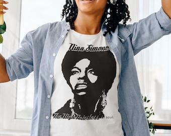 May include: A white t-shirt with a black and white image of Nina Simone. The text "Nina Simone" and "The High Priestess of Soul." is printed on the shirt.