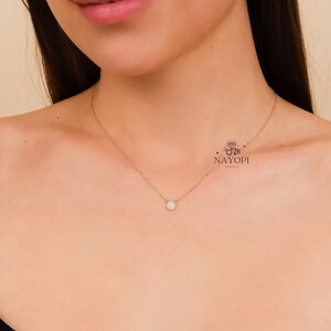 Minimalist round diamond pendant necklace with small pave diamonds.