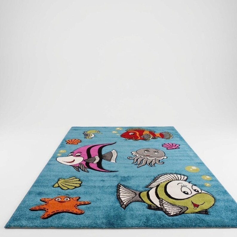 May include: A rectangular blue rug featuring cartoon sea creatures. The rug has a light blue background with illustrations of colorful fish, starfish, jellyfish, and seashells. The design is playful and suitable for a child's room.