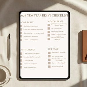 May include: A digital tablet displays a 2026 New Year Reset Checklist. The checklist is divided into Home, Mental, Digital, and Life Reset sections. A pen and a cup of coffee sit to the left of the tablet, and a wooden block is on the right.