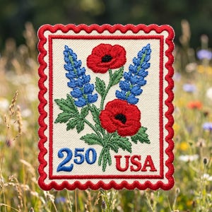 May include: A rectangular embroidered patch with a scalloped red border on a cream background. It features two red poppies and two blue lupine flowers with green leaves. The text 250 in blue and USA in red is printed at the bottom.