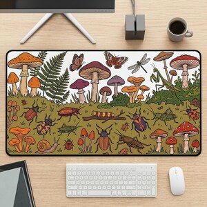 May include: A rectangular desk mat featuring a detailed illustration of various mushrooms, ferns, and insects including beetles, a snail, a praying mantis, and butterflies on a green background with a white upper section.