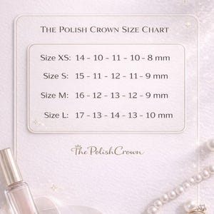 May include: A size chart for The Polish Crown nail products, with measurements in millimeters. The chart includes sizes XS, S, M, and L, with corresponding nail measurements. A bottle of nail polish, a ring, and pearls are also visible.