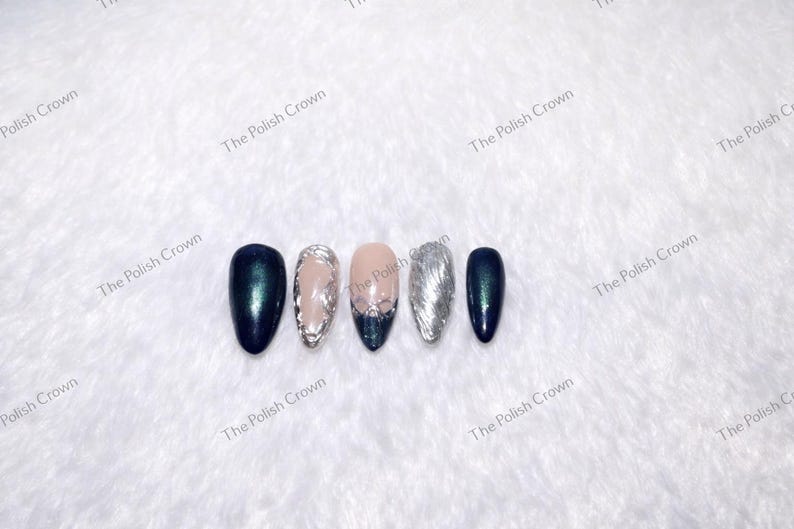 May include: Five artificial nails in a row, each with a different design. The nails are oval-shaped and feature colors like dark teal, silver, and nude. Some nails have glitter or decorative elements. The Polish Crown is printed on the background.