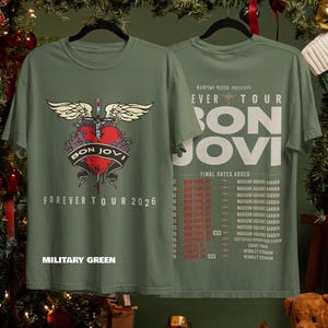 May include: A military green t-shirt featuring a Bon Jovi Forever Tour 2026 graphic on the front with a winged heart and sword. The back displays the tour name, Hampton Water presents, and a list of final tour dates in New York and Europe.