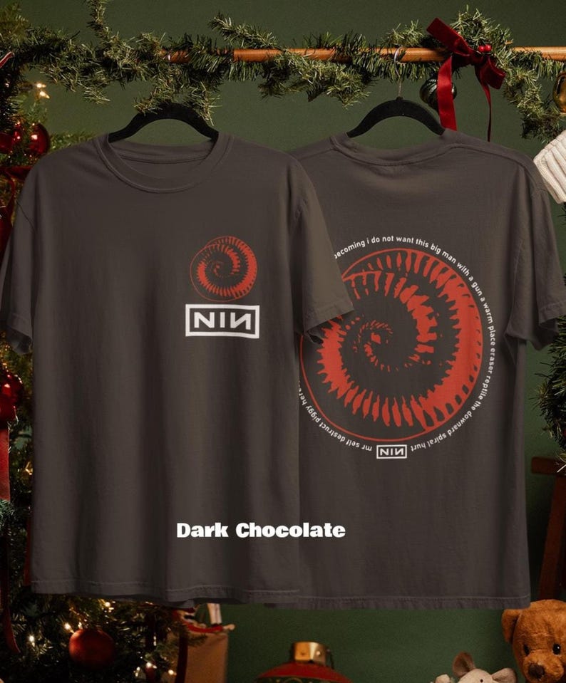 May include: Dark chocolate-colored t-shirt featuring a red spiral design and the text "NIN" in a white box. The back of the shirt has a matching spiral design and text. The shirt is displayed on a black hanger.