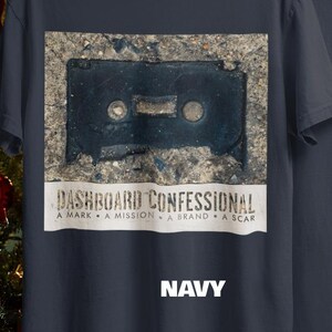 May include: Navy blue t-shirt featuring a distressed image of a cassette tape. Below the image is the text "DASHBOARD CONFESSIONAL" and the words "A MARK &bull; A MISSION &bull; A BRAND &bull; A SCAR". The word "NAVY" is printed in white.