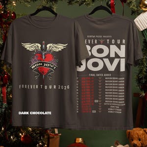 May include: A dark chocolate colored t-shirt featuring a front graphic of a red heart pierced by a sword with wings and the text Bon Jovi Forever Tour 2026. The back displays the tour schedule with dates and locations including Madison Square Garden.