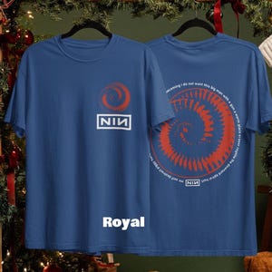 May include: Royal blue t-shirts with a red spiral design and the text "NIN". One shirt displays the logo, the other has a spiral and text. The word "Royal" is printed on the front of one shirt.