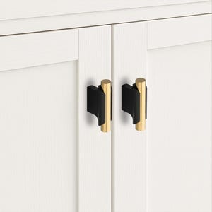 May include: Two cabinet knobs featuring a vertical cylindrical gold-toned metal bar attached to a matte black rectangular base. The hardware is mounted on white cabinet doors with a subtle wood grain texture, showcasing a clean and functional design.