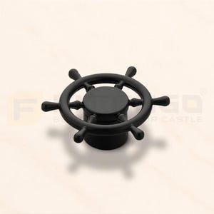 May include: A matte black cabinet knob shaped like a ship's steering wheel. The circular handle features eight spokes radiating from a central hub, mounted on a cylindrical base. The design is uniform in color and features a smooth, solid finish.