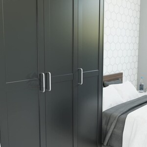 Könnte beinhalten: Ein hoher, dunkel anthrazitfarbener Kleiderschrank mit drei vertikalen Türen, klaren Linien und einfachen, silberfarbenen Metallgriffen. Der Schrank hat eine glatte, matte Oberfläche und einen strukturierten, rechteckigen Rahmen.