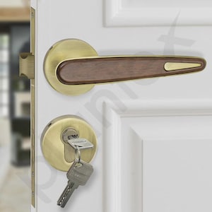 May include: A door handle set featuring a brushed brass finish with a dark wood inlay on the lever. The set includes a circular escutcheon plate with a keyhole and a metal key inserted, mounted on a white paneled door with a brass edge plate.