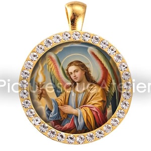 May include: Gold-tone pendant with a detailed image of an angel holding a torch. The angel has colorful wings and is surrounded by a halo. The pendant is round and framed with clear crystals. The text "Picturesque Atelier" is visible.