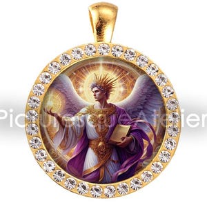 May include: Gold-tone pendant with a round, crystal-studded frame. The pendant features a detailed illustration of an angel with white wings, holding a book and wearing a purple robe. The pendant has a gold bail.