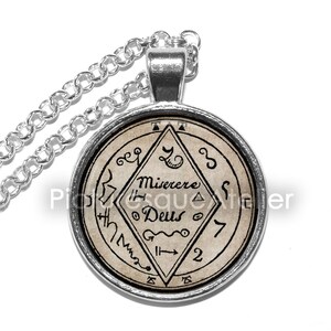May include: Silver chain necklace with a round pendant featuring a vintage-style image of a sigil with the text "Miserere Deus" and other symbols.
