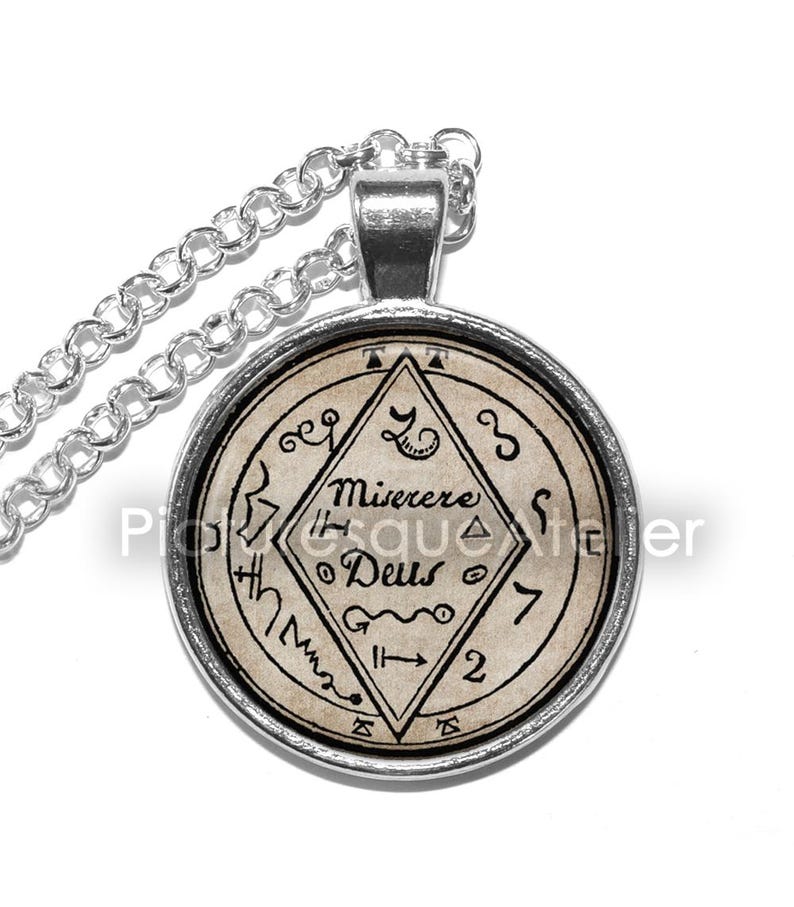 May include: Silver chain necklace with a round pendant featuring a vintage-style image of a sigil with the text "Miserere Deus" and other symbols.