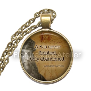Może przedstawiać: Bransoletka z brązu z okrągłym szklanym wisiorkiem przedstawiającym wizerunek Leonarda da Vinci z czasów starożytnych i cytat: "Sztuka nigdy nie jest skończona, tylko porzucona. - Leonardo da Vinci"