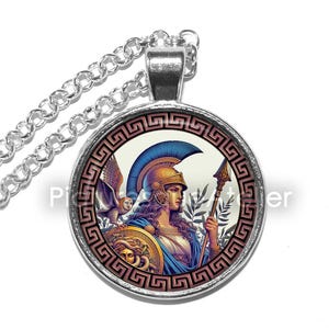 May include: A silver necklace with a round glass pendant featuring a colorful illustration of a woman in a helmet holding a spear. The woman is surrounded by a decorative border with a Greek key pattern.