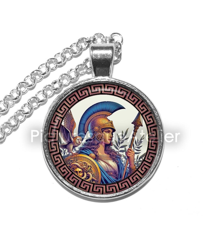 May include: A silver necklace with a round glass pendant featuring a colorful illustration of a woman in a helmet holding a spear. The woman is surrounded by a decorative border with a Greek key pattern.