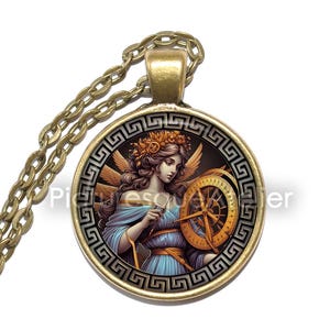 May include: A gold necklace with a round pendant featuring a woman with wings and a compass. The pendant has a black and gold Greek key border.