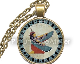 May include: A gold chain necklace with a round pendant featuring a colorful image of the Egyptian goddess Isis with outstretched wings. The pendant has a black background with a blue and gold border.