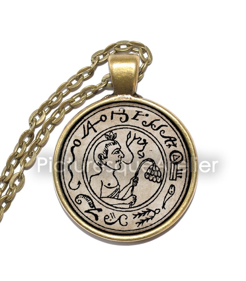 May include: A gold chain necklace with a round pendant featuring a black and white illustration of a person holding a flower. The pendant has a gold rim and the text "E.I.S.S.A.O.I" around the edge.